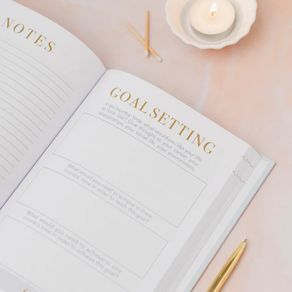 Mind Notes journal open at the goal setting page beside a candle