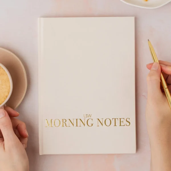 Cream Morning Notes journal cover with a hand holding a gold pen