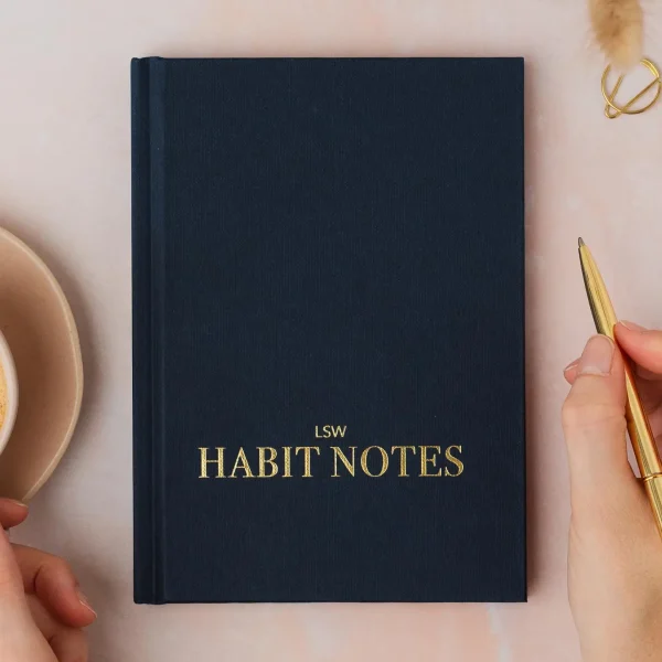 Navy Habit Notes journal cover with a hand holding a gold pen